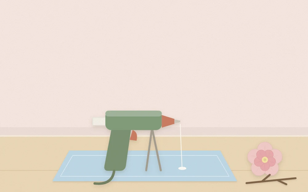 Hot glue gun resting on a small stand over a silicone mat with a felt flower and twig