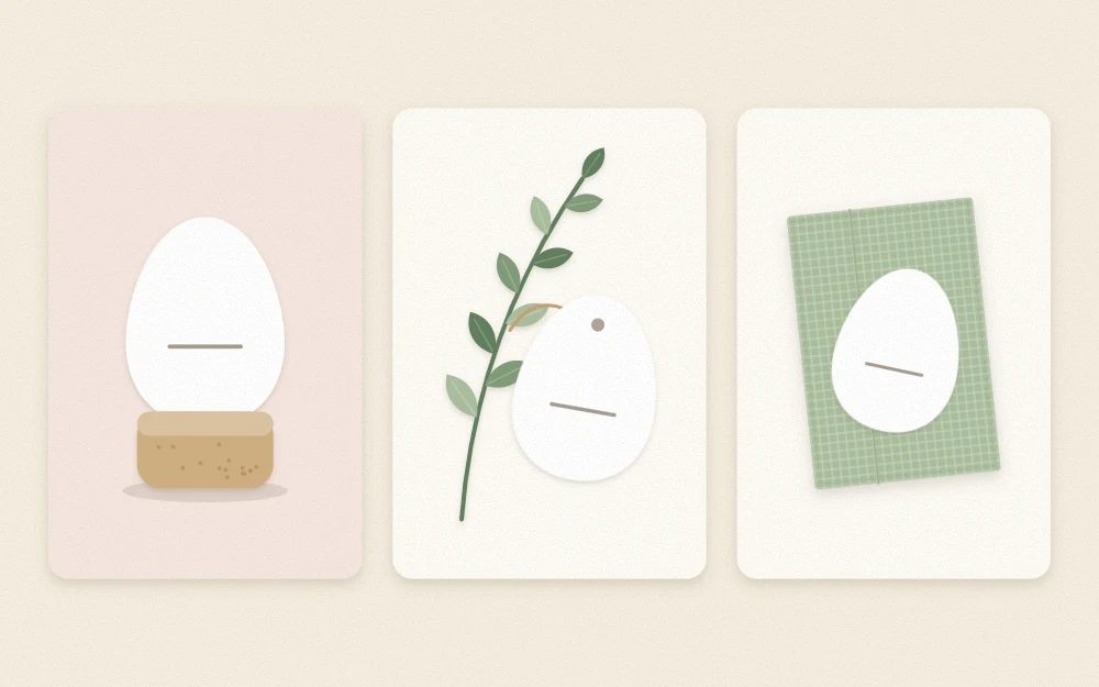 Three blank egg-shaped name cards: propped in a cork, tied to a sprig, laid on a napkin