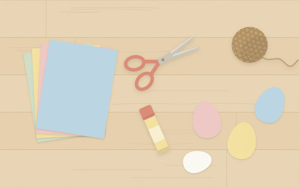 Work table from above with pastel cardstock, scissors, glue stick, twine and cut paper eggs