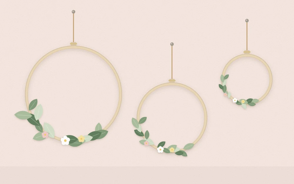 Three hoop wreaths of different sizes hanging as a group on a wall with small greenery clusters