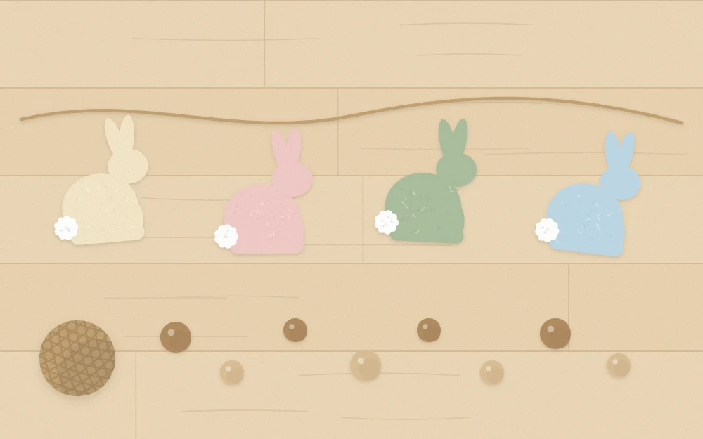 Finished felt bunnies and loose wooden beads laid out along a length of twine on a table