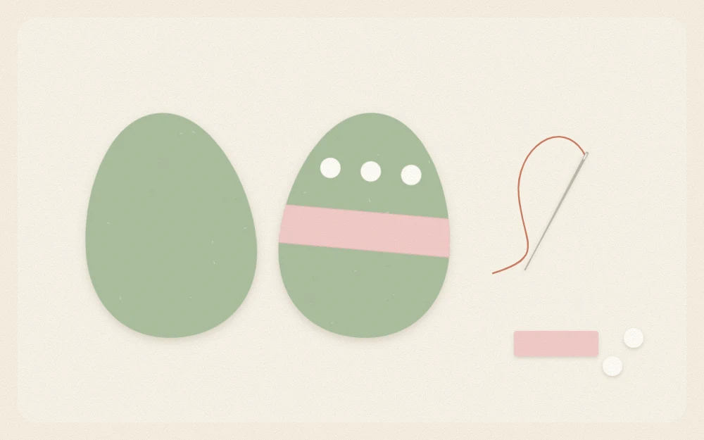 Two felt egg shapes with a band and three dots on the front, needle and thread beside them
