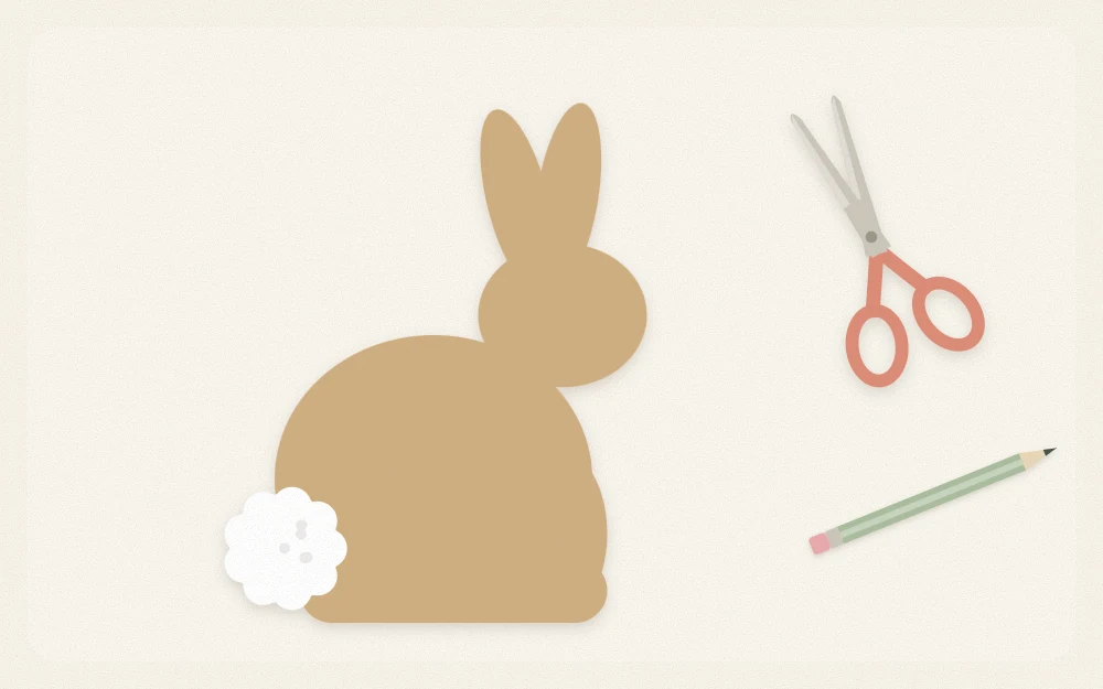 A kraft paper bunny silhouette with a small white pompom tail beside scissors and a pencil