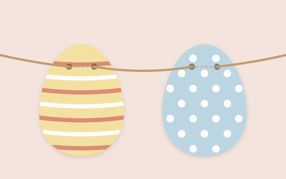 Close-up of two paper eggs on twine, each with two punched holes and the twine passing behind