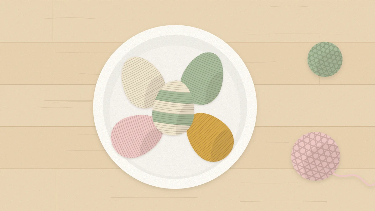 Five yarn-wrapped eggs in cream, sage, blush and mustard, one striped in two colors, resting in a small bowl